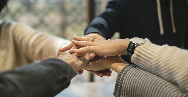 Accessing Mental Health Resources A photo of people placing their hands on top of each other to show solidarity.
