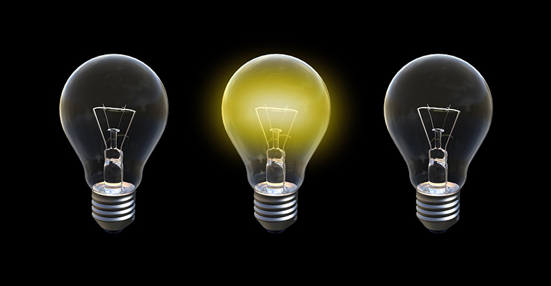 A photo with a black background with three light bulbs placed beside each other and only the bulb in the centre is lit.