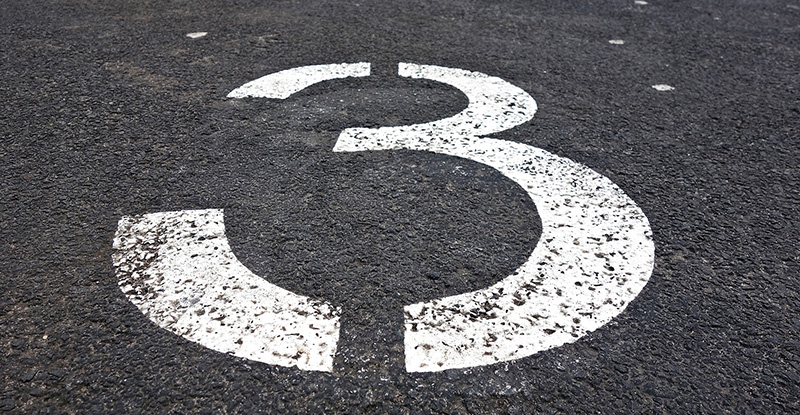 A photo of a road with the number three drawn on it.