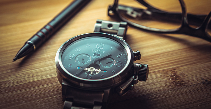 Requesting an Assignment Extension A close-up photo of a table with a watch, a pen, and glasses in focus.
