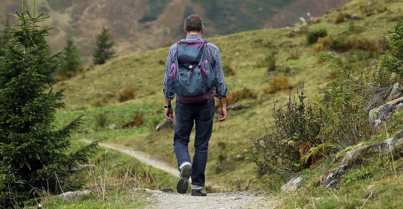 Tough Love: This journey is difficult A photo of a man walking with a backpack through a trail.