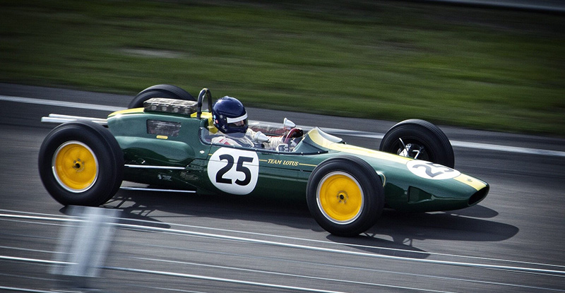 A photo of a person driving a dark green racing car with the number 25 on it.
