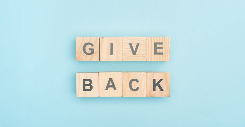 A photo of a light blue background with letter blocks that read " Give back".