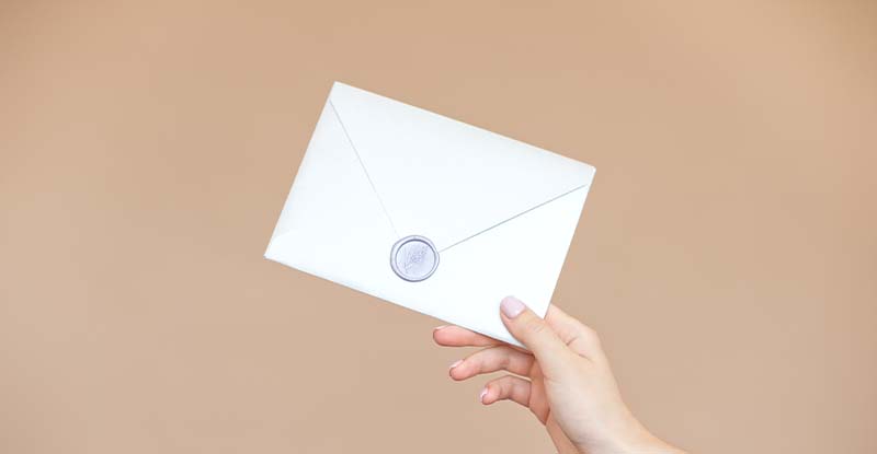 Official Transcripts A photo featuring a light brown background with a person holding a sealed envelope.
