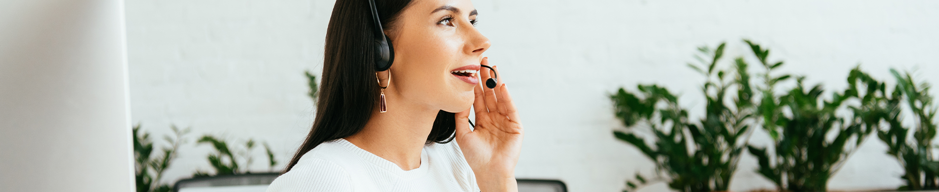 A Caucasian woman wearing a headset, smiling and looking away.