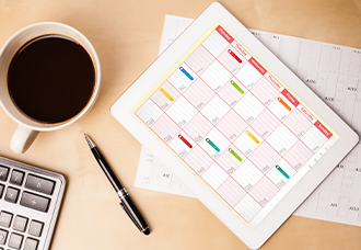 A photo taken from above, showing a coffee cup, pen, calculator, and a calendar placed on a table.