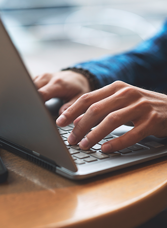 A photo focusing on a person’s hand typing on a laptop, with only the hand and keyboard visible to emphasize the action.